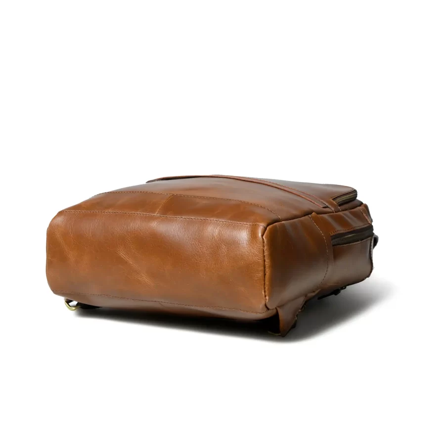 Bottom side view of a tan brown leather backpack with 3